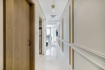 a hallway with white walls and a wooden door at Daniels Stylish 1BR at Silverene Tower Dubai Marina in Dubai