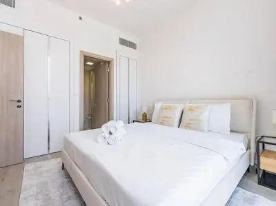 a white bedroom with a large white bed with towels on it at Modern Spacious- 2 BR with Pool & Gym- Luma 22 JVC in Dubai