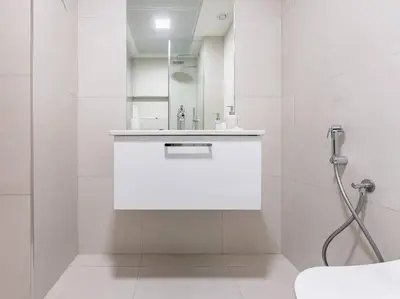 a white bathroom with a sink and a mirror at Modern Spacious- 2 BR with Pool & Gym- Luma 22 JVC in Dubai