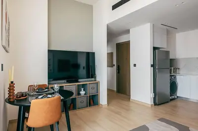 a living room with a table and a kitchen at Beautiful 1BR - City View - Pool - Free Parking in Dubai