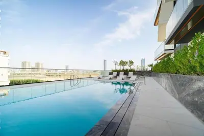 a swimming pool with white chairs next to a building at Beautiful 1BR - City View - Pool - Free Parking in Dubai