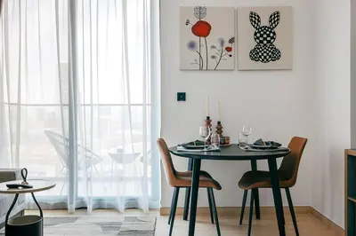 a dining room with a table and chairs and a window at Beautiful 1BR - City View - Pool - Free Parking in Dubai