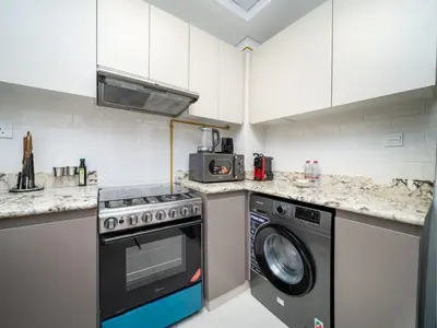 a kitchen with a stove and a washing machine at Chic 1 Bed Getaway in Al Jaddaf Easy City Access in Dubai