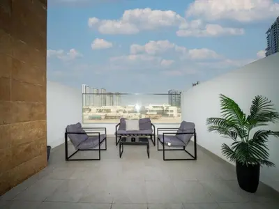 a balcony with chairs and a table and a plant at Elegant Studio in Azizi Riviera, Meydan in Dubai