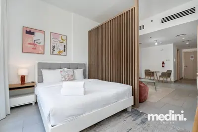a bedroom with a large white bed and a desk at Large studio in JVC - Dubai in Dubai