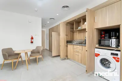 a kitchen with a washing machine and a table at Large studio in JVC - Dubai in Dubai