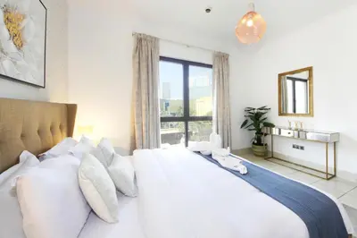 a bedroom with a large white bed with a window at Elegant 2BR Apartment in Yansoon 3 with Burj Khalifa Views in Dubai