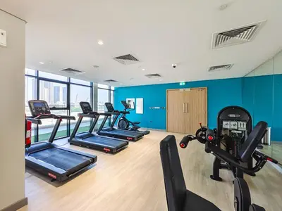 a gym with several treadmills and a row of exercise bikes at Relaxing Studio Retreat in Vibrant Meydan City in Dubai