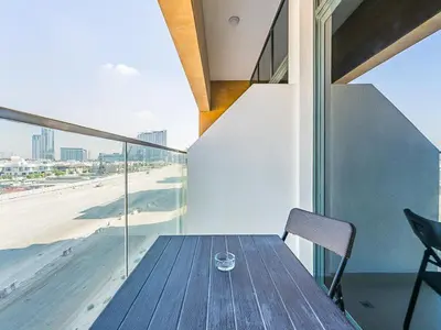 a wooden table on a balcony with a view of the beach at Relaxing Studio Retreat in Vibrant Meydan City in Dubai