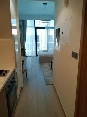 a hallway of a hotel room with a bed and a kitchen at Stonetree - Studio Unit at Azizi Riviera 45 in Dubai
