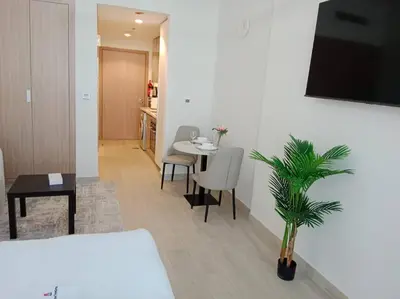 a living room with a table and a palm tree at Stonetree - Studio Unit at Azizi Riviera 45 in Dubai