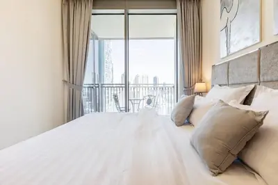 a bedroom with a white bed with a large window at Large 2BR with Marina and Sea View in 5242 Tower - EE Holiday Homes in Dubai