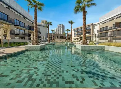 a swimming pool with palm trees and buildings at Luxury Apartment in Oakley Square Residences, JVC in Dubai
