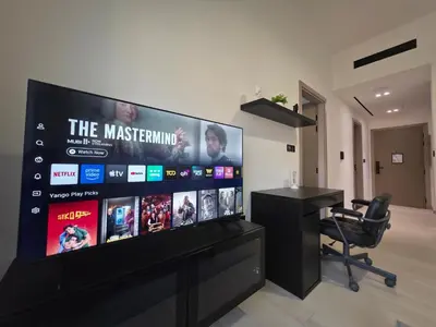 a large flat screen tv in a room with a desk at 1 Bed Retreat- RBE Vacation Homes-Binghatti Luna in Dubai