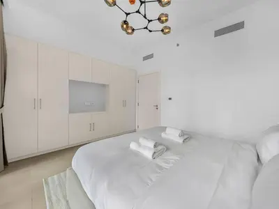 a white bedroom with a bed and a chandelier at 2BR near Dubai Mall, Burj views! in Dubai
