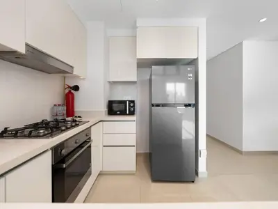 a kitchen with a stainless steel refrigerator and white cabinets at 2BR near Dubai Mall, Burj views! in Dubai