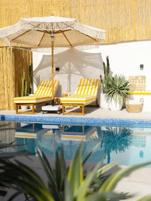two yellow chairs and an umbrella next to a swimming pool at Unique Beachside Studio, Shared Pool & Burj Khalifa View! in Dubai