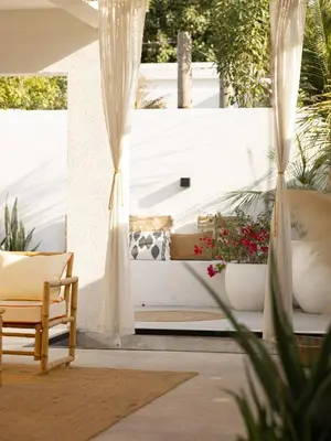 a patio with a couch and a chair and flowers at Unique Beachside Studio, Shared Pool & Burj Khalifa View! in Dubai