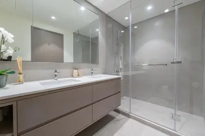 a bathroom with two sinks and a glass shower at Direct Burj Khalifa View I Minutes Walk to Dubai Mall I Stunning Fountain Views I One Lux Stay Grande Signature Residence in Dubai