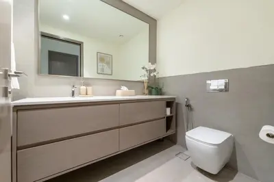 a bathroom with a sink and a toilet and a mirror at Direct Burj Khalifa View I Minutes Walk to Dubai Mall I Stunning Fountain Views I One Lux Stay Grande Signature Residence in Dubai