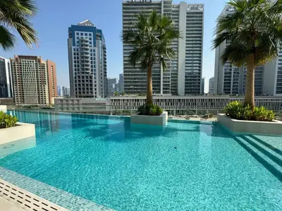 a large swimming pool with palm trees in a city at Luxury Living Studio in the Heart of Business Bay in Dubai