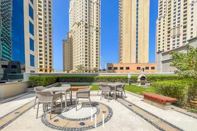a patio with tables and chairs and tall buildings at LUX The Shemara Marina View Suite in Dubai