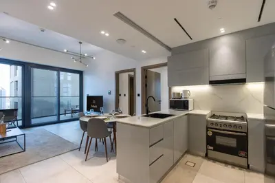 a kitchen with white cabinets and a dining room with a table at Livbnb-Classy 2B with Jacuzzi & BurjKhalifa View in Dubai