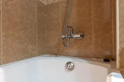 a bath tub with a shower head in a bathroom at Waves - Cozy Studio with Balcony & Partial Lake Views in Dubai