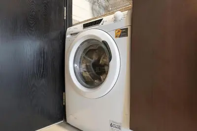 a washing machine sitting next to a door at Waves - Cozy Studio with Balcony & Partial Lake Views in Dubai