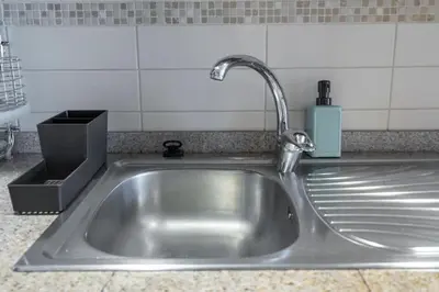 a stainless steel kitchen sink with a faucet at Waves - Cozy Studio with Balcony & Partial Lake Views in Dubai