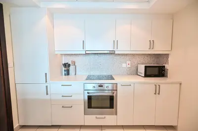 a kitchen with white cabinets and a microwave at Luxury 1 Bed with full Marina View - Emaar Park Island in Dubai