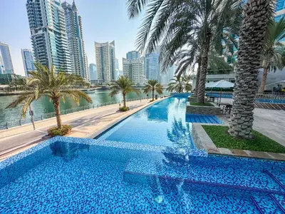 a swimming pool with palm trees and a city at Luxury 1 Bed with full Marina View - Emaar Park Island in Dubai