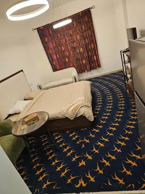 a bedroom with a bed on a blue rug at Room with Kitchen Furnished Apartments by oima leasing property in Dubai