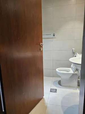 a bathroom with a toilet and a wooden door at Room with Kitchen Furnished Apartments by oima leasing property in Dubai