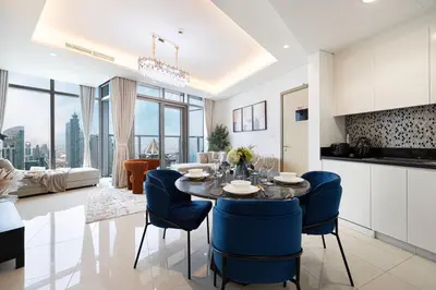 a kitchen and living room with a table and blue chairs at Highest Infinity Pool Burj Khalifa View in Dubai