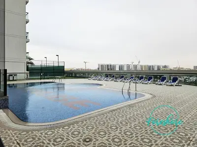 a large swimming pool with chairs and a building at Blissful One Bedroom Apartment in Dubai