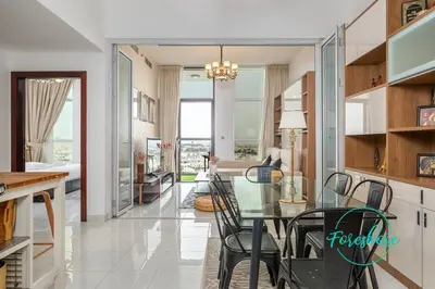 a dining room and living room with a glass table at Blissful One Bedroom Apartment in Dubai