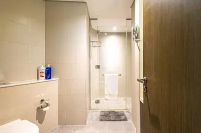 a bathroom with a shower and a toilet and a door at Spacious Studio with Pool - Canal & Burj Views in Dubai