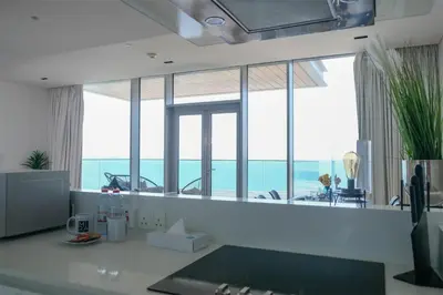 a kitchen with a large window with a view of the ocean at Mira Holiday Homes - Luxury 1 bedroom with sea view in Dubai