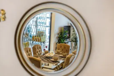 a mirror reflecting a living room with a table and chairs at Royal Marina Experience Lavish 2BR Waterfront View in Dubai