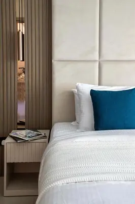 a bed with a blue pillow and a side table at Frank Porter - Al Samar 1 in Dubai