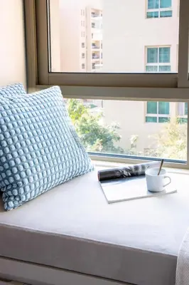a bed with a cup of coffee and a book and a window at Frank Porter - Al Samar 1 in Dubai