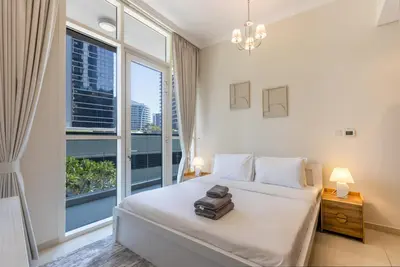 a bedroom with a bed and a large window at Livbnb - 2B Maid's in Dunya, 5Min Walk to Dubai Mall in Dubai