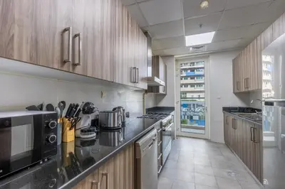 a kitchen with wooden cabinets and a counter top at Livbnb - 2B Maid's in Dunya, 5Min Walk to Dubai Mall in Dubai