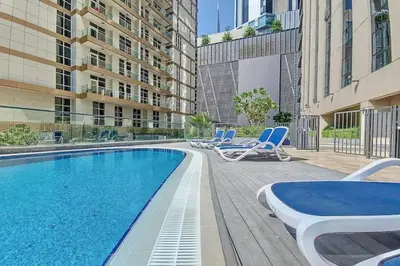 a swimming pool with lounge chairs next to a building at Livbnb - 2B Maid's in Dunya, 5Min Walk to Dubai Mall in Dubai