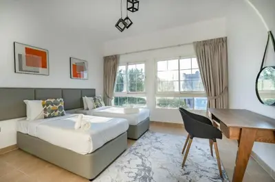 a bedroom with two beds and a desk and a table at Beautiful 2BR Villa in JVT in Dubai