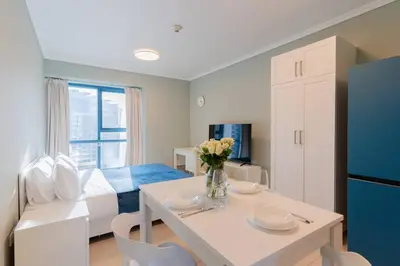 a living room with a white table and a blue refrigerator at JLT Nice Studio apartment High floor View in Dubai