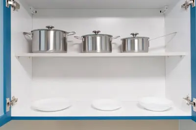 three pots and pans on a shelf in a kitchen at JLT Nice Studio apartment High floor View in Dubai