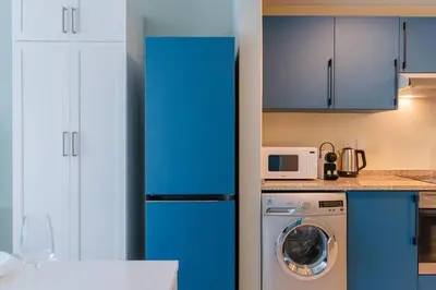 a kitchen with blue cabinets and a washing machine at JLT Nice Studio apartment High floor View in Dubai