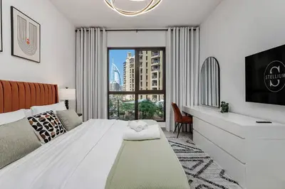 a bedroom with a white bed and a large window at Asayel Apartments in Dubai